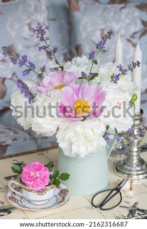 bouquet of white peony flowers and catnips in vintage milk can in garden