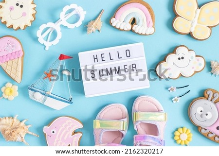 Hello summer text on lightbox and cute summer symbols on blue background. Top view, Flat lay. Creative summer concept, greeting card.