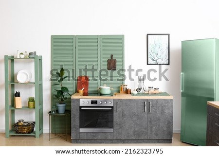 Modern interior of comfortable kitchen with fridge, oven and folding screen