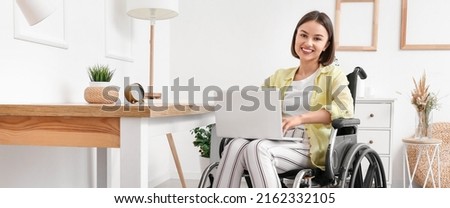 Young woman in wheelchair using laptop at home Royalty-Free Stock Photo #2162332105