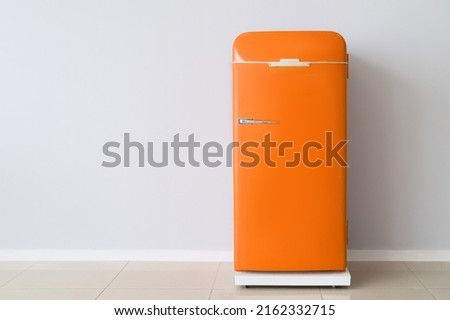 Stylish retro fridge near light wall  