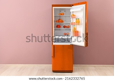 Big open fridge with fresh products near color wall