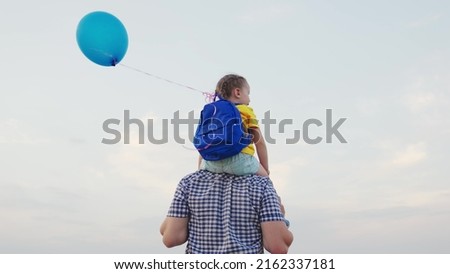 little girl sits shoulders of her dad against sky with balloon. happy family. hold gel ball with hand child kid. chidhood dream. papa day. childhood summer travel with backpack. concept happy family