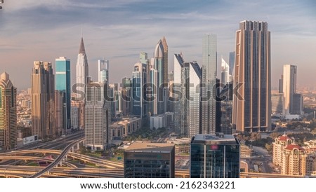 Panorama of Dubai Financial Center district with tall skyscrapers timelapse. Aerial view to towers along busy highway during sunset Royalty-Free Stock Photo #2162343221
