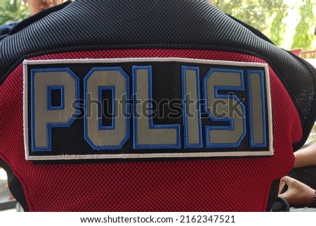 A vest with the words POLISI or police on the back of an Indonesian police officer.