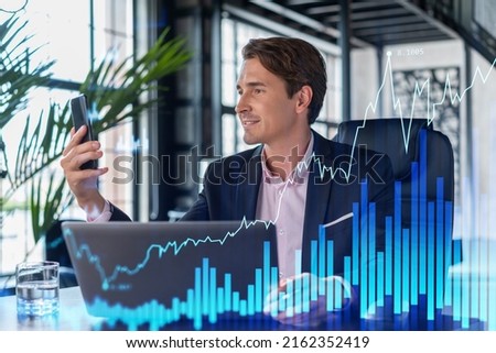 Businessman in suit using smart phone to optimize trading strategy at corporate finance fund. Forex chart hologram over modern panoramic office background