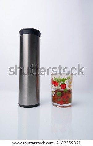 Stainless steel thermos bottle and glass filled with tea water isolated on white background