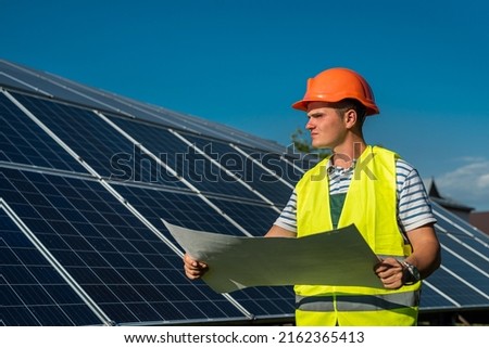 young engineer near solar panel and worker holding blueprint, photovoltaic. alternative energy