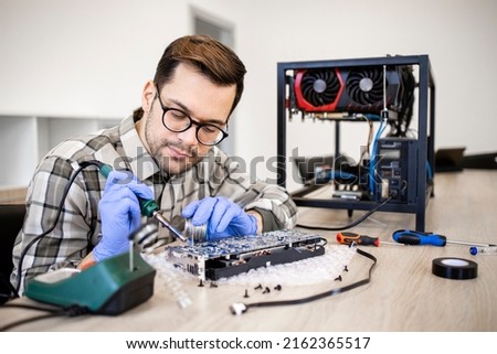 Professional serviceman repairing graphics card and soldering printed circuit board. Royalty-Free Stock Photo #2162365517