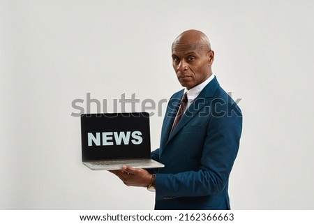 Confident african american ceo manager holding laptop computer with 'news' word. Adult man wearing suit. Modern successful male lifestyle. Isolated on white background. Studio shoot. Copy space