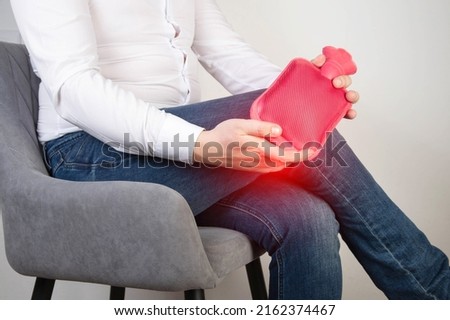 A male office worker holds a heating pad with hot water near the knee joint. Treatment of knee pain with heat therapy, rheumatoid arthritis Royalty-Free Stock Photo #2162374467