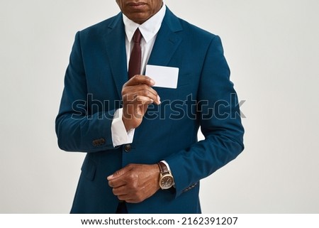 Cropped image of black businessman showing business card. Obscure face of adult man wearing formal wear. Modern successful male lifestyle. Isolated on white background. Studio shoot. Copy space