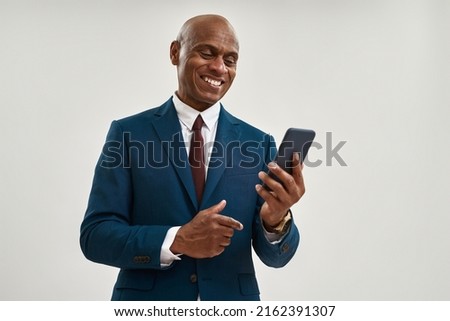 Smiling black businessman watching mobile phone. Bald adult man wearing formal wear. Concept of modern successful male lifestyle. Isolated on white background. Studio shoot. Copy space Royalty-Free Stock Photo #2162391307