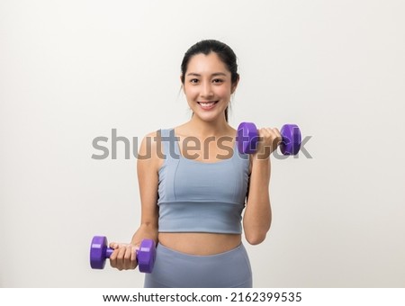 Sporty Asian woman exercises with dumbbells on isolated white background. Good shape and health fitness woman weight training standing pose smile to camera. Royalty-Free Stock Photo #2162399535