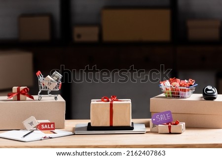Gift boxes, laptop and toy cart with money on table