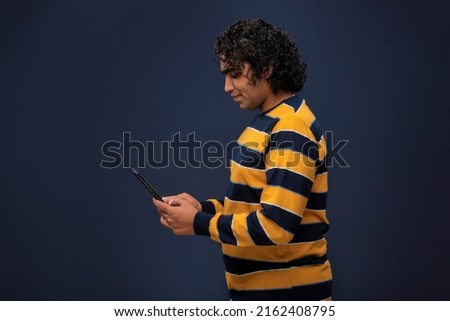 Young handsome young man holding and using smartphone or mobile or tablet phone on grey background 