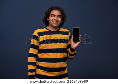 Young handsome young man, businessman showing a blank screen of a smartphone or mobile or tablet phone on grey background 