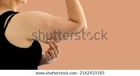 A young Asian woman grabbing skin on her upper arm with excess fat isolated on a white background. Pinching the loose and saggy muscles. Overweight concept Royalty-Free Stock Photo #2162433183