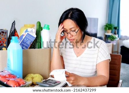 Living cost inflation crisis high cost in gas electric energy woman holding receipts from supermarket with calculator by rising grocery prices and surging cost as an inflation financial crisis. Royalty-Free Stock Photo #2162437299