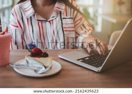 Woman preparing to take pictures of Piccolo Latte coffee cup, brownies and breakfast on wooden table with smartphone.