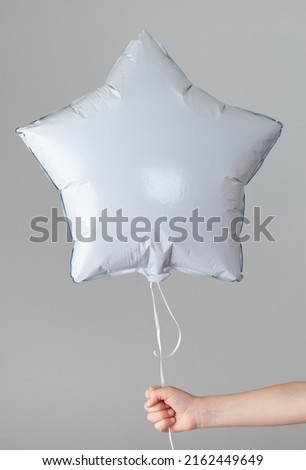 Gray balloon in the shape of a star in the hand.