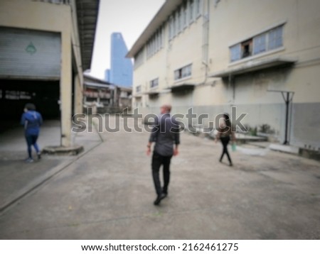 Blurry abstract background of man and woman walking among buildings.