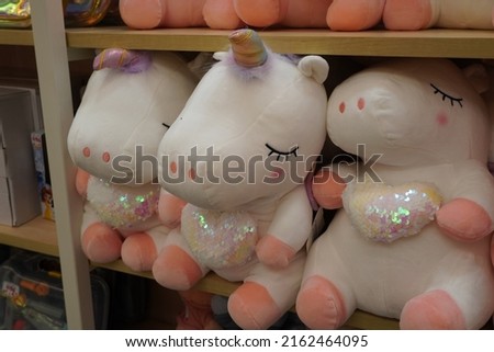 Unicorn plush toys in a store shelf for sale. Cute soft unicorn. Childrens girly pink unicorn stuffed animal plush toy. White Unicorn plush figure and many Colorful plush toys.