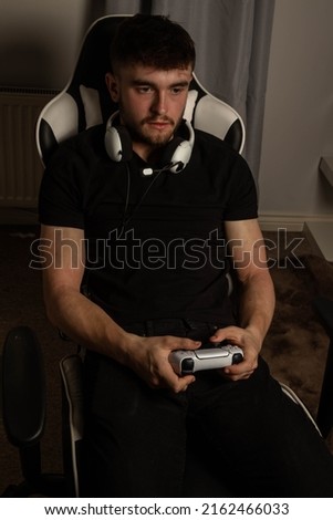 A University Aged Male Student playing a video game while wearing a headset