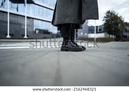 Fashion abstract picture of a woman in a gray raincoat and black boots.