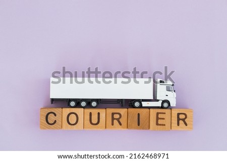Toy truck with wooden box on purple background. Courier