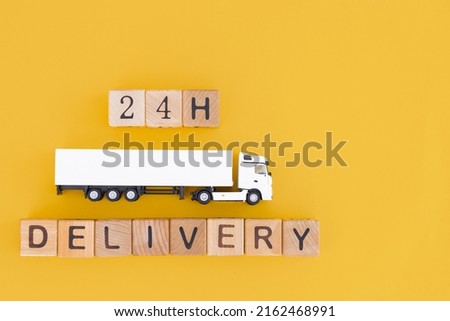 Toy truck with wooden box on yellow background. 24h Delivery concept