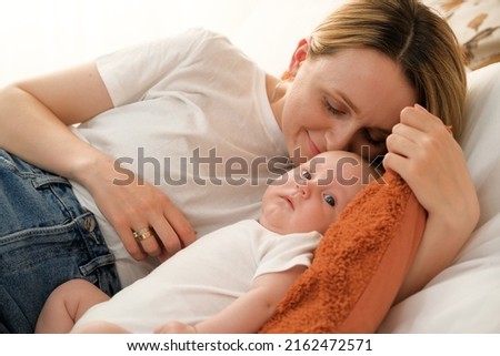 mom with a newborn baby lies on the bed. mother kisses the child. mother's love .