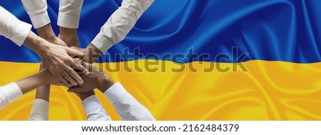 Hands of people united on ukrainian flag hands together over the national flag of Ukraine, in demonstration of union against the war escalation