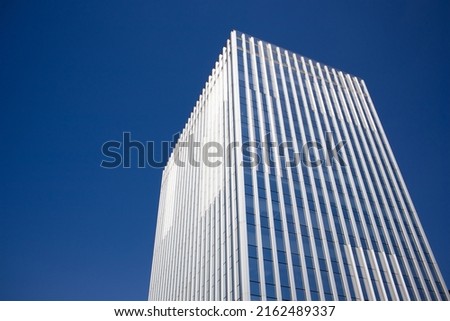 Modern tall multistory building glass facade against blue sky with space for text. Construction of residential buildings, office buildings, facilities. Construction business. Real estate investment. Royalty-Free Stock Photo #2162489337