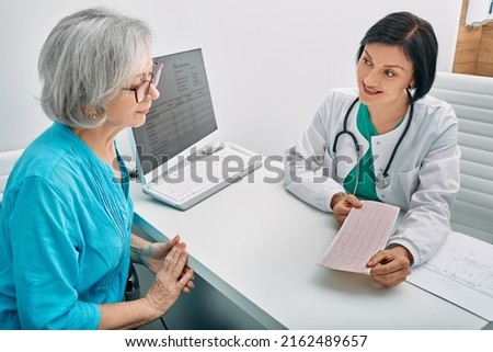 Positive doctor consulting senior woman on results of cardiogram and test. Diagnostic heart diseases, heart attacks, and tachycardia in elderly people Royalty-Free Stock Photo #2162489657