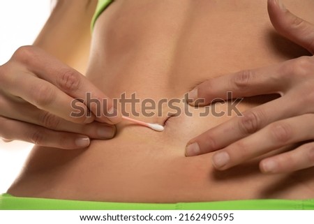 Woman cleaning her belly button with cotton swab , Cropped image, close up. Royalty-Free Stock Photo #2162490595