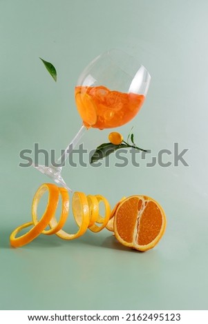 Glass of aperol spritz cocktail, with orange peel, photo with a balancing object on a green background . Royalty-Free Stock Photo #2162495123
