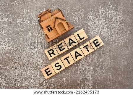 Real estate text on wooden blocks with house model.