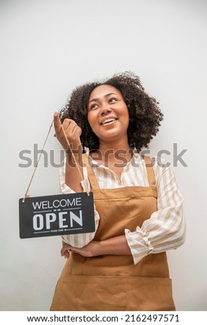 Business owner young woman in apron hanging open sign on front door welcoming.