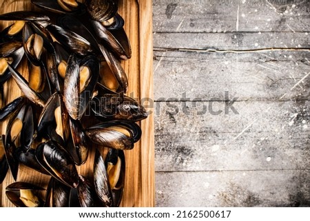 A bunch of boiled mussels on a wooden cutting board. On a gray background. High quality photo