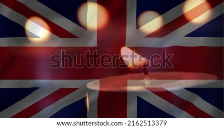 Digital composite of British flag with candles in the background. One candle going out  Royalty-Free Stock Photo #2162513379