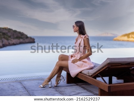 Photo of a young woman sitting near pool and enjoying the view. Luxury resort  Royalty-Free Stock Photo #2162529237