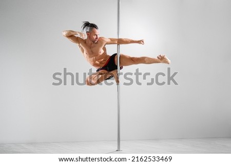 Fit pole athlete does trick on the pole, pole dancing  Royalty-Free Stock Photo #2162533469