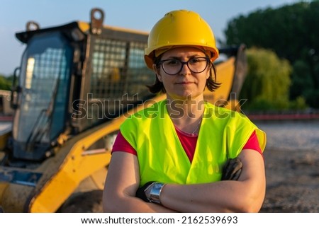 Cheerful female excavator operator on construction site. Woman construction apprentice learning to drive heavy equipment Royalty-Free Stock Photo #2162539693