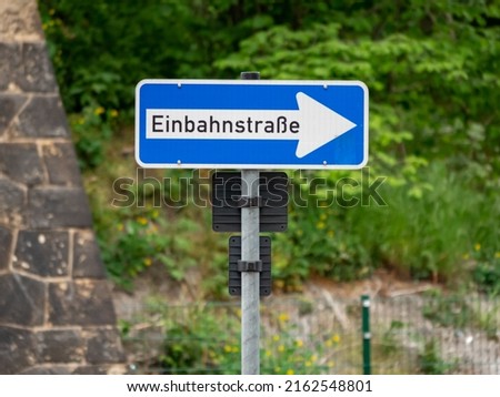 One way sign in German language "Einbahnstraße". The white arrow is showing the direction of traffic. Road users must follow the information on the traffic sign. The arrow is pointing to the right.