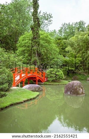 Japanese garden with a traditional red bridge among lush vegetation