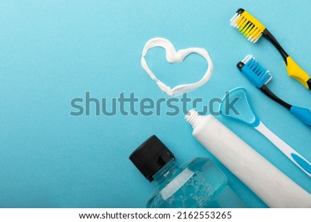 Heart symbol made from toothpaste. A tube of toothpaste and a toothbrush on a blue background. Refreshing and whitening toothpaste. Copy space for text. flat lay