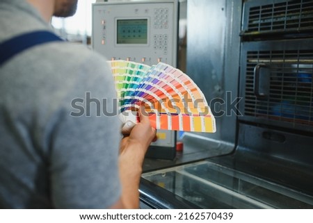 Man working in printing house with paper and paints.