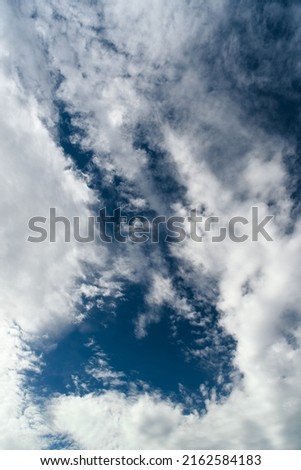 Blue sky with cumulus white clouds. Beautiful cloudscape. Abstract background. Vertical orientation