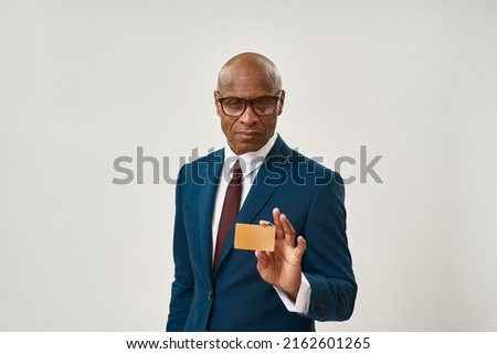 Confident african american businessman showing golden business card. Adult man wearing suit and glasses looking at camera. Modern successful male lifestyle. White background. Studio shoot. Copy space